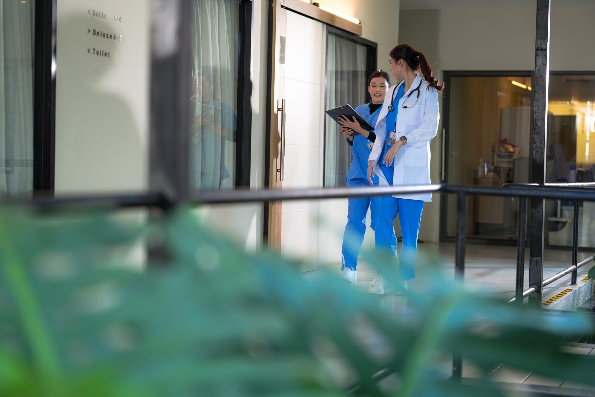 Doctor and nurse reviewing a clipboard in a clinic corridor