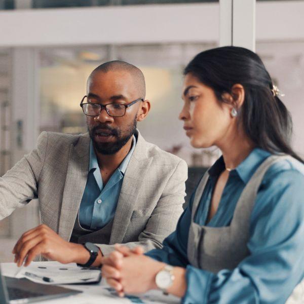 Two professionals discussing work over a laptop in an office