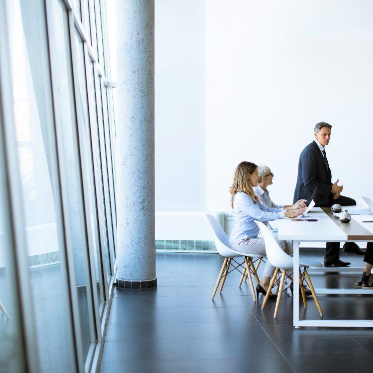 Five colleagues meeting around a white table in a bright, open office