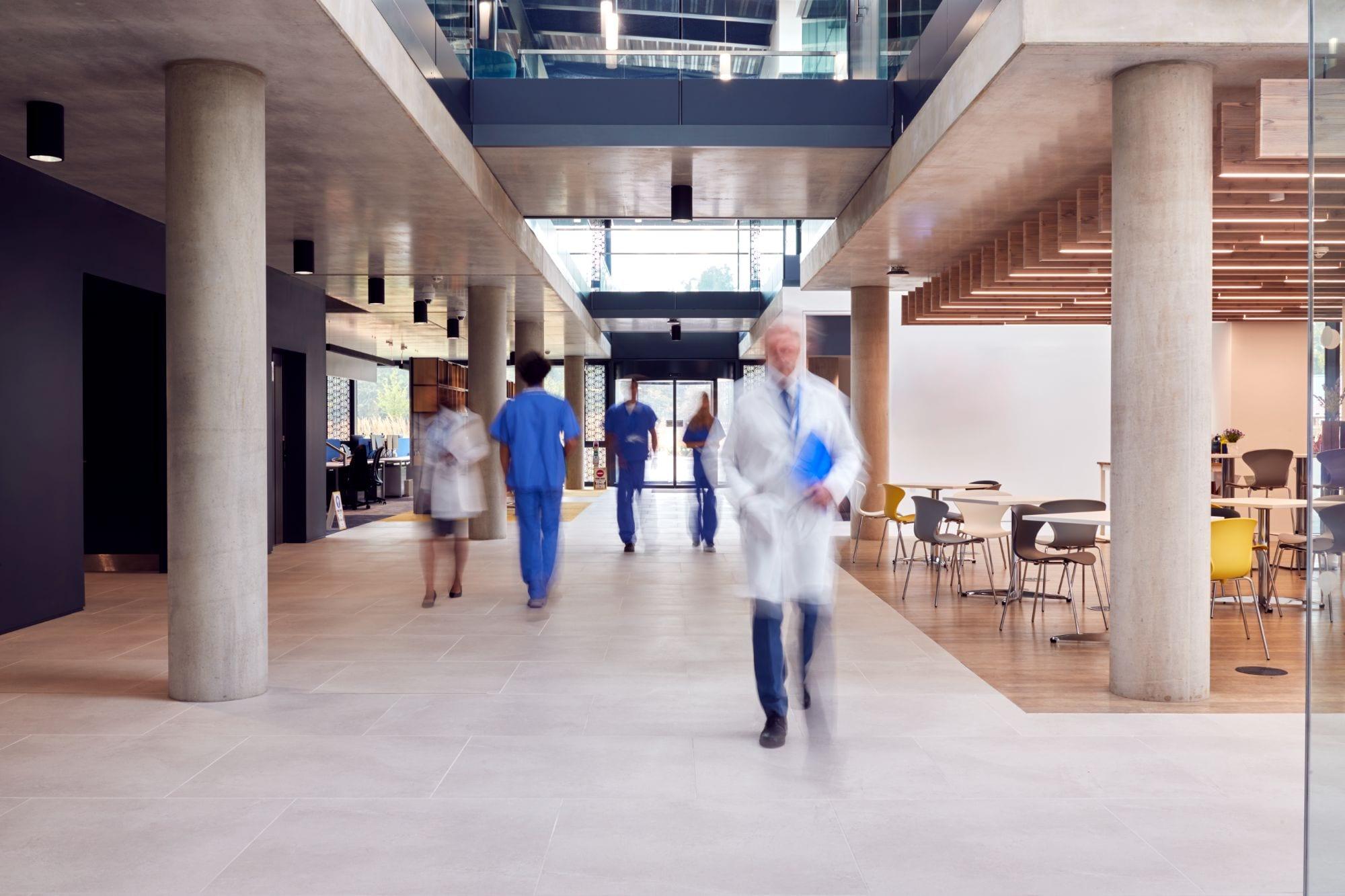 Clinical staff crossing a modern hospital atrium