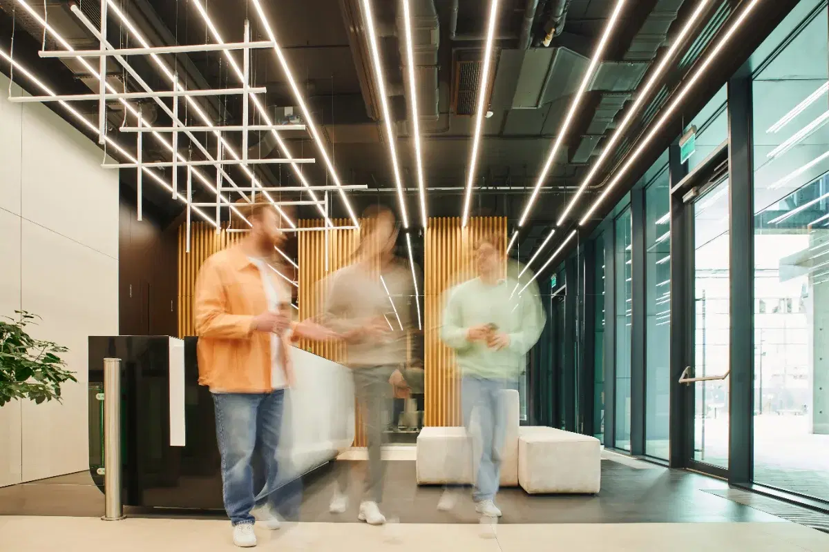 Three colleagues walking through a modern office lobby under linear ceiling lights
