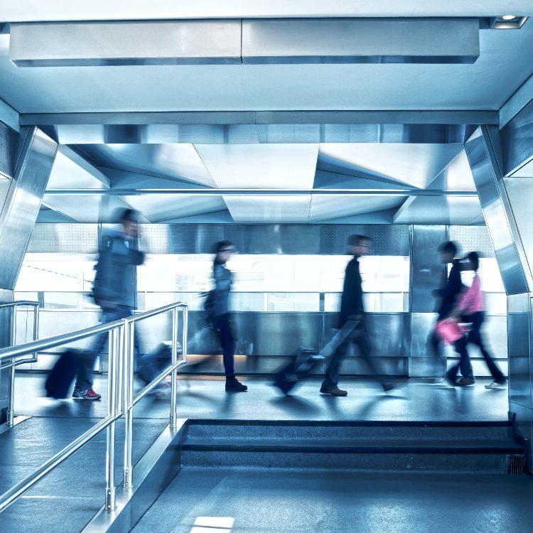 Travellers with luggage walking through a steel transit corridor
