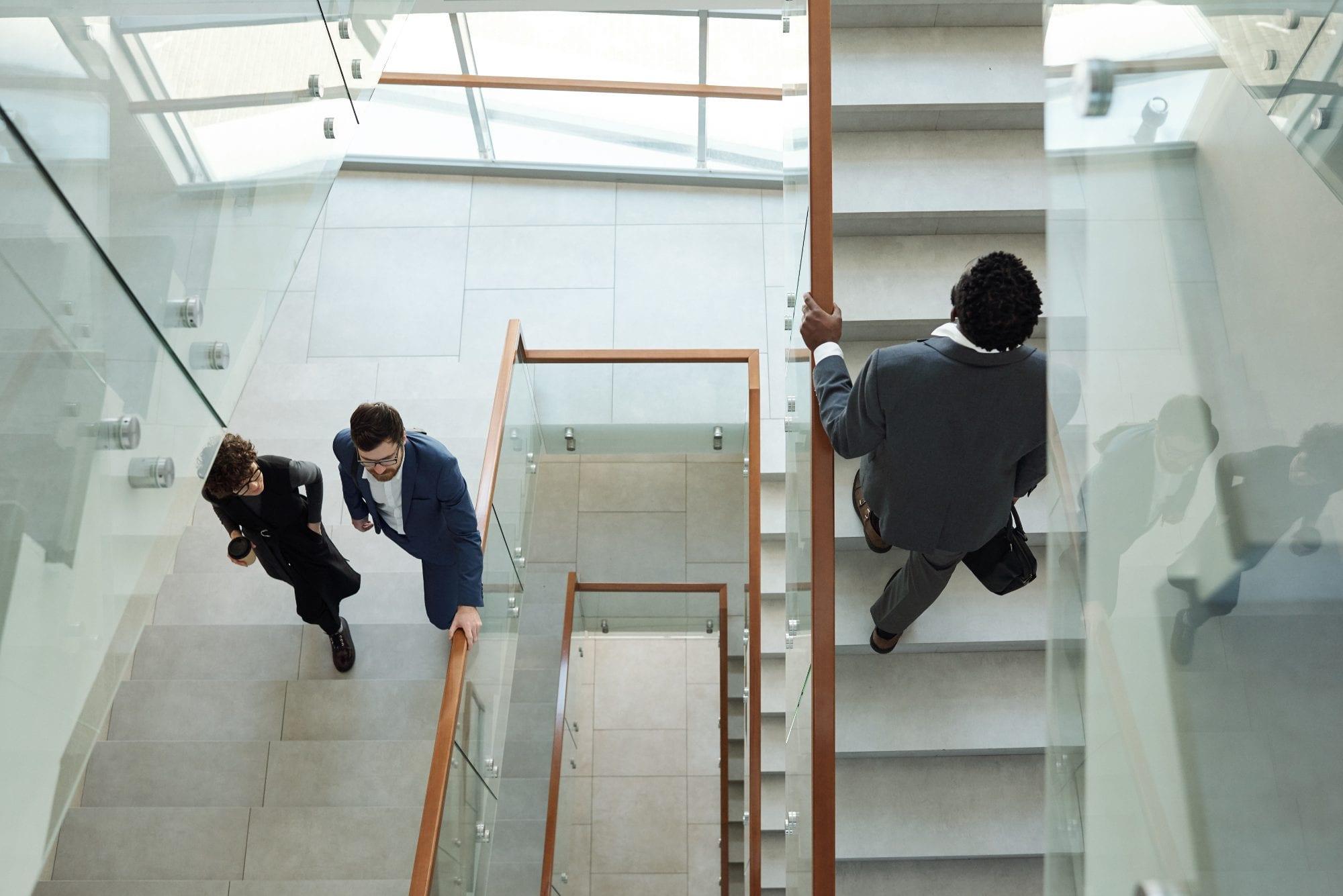 Professionals walking down a staircase in a modern office lobby